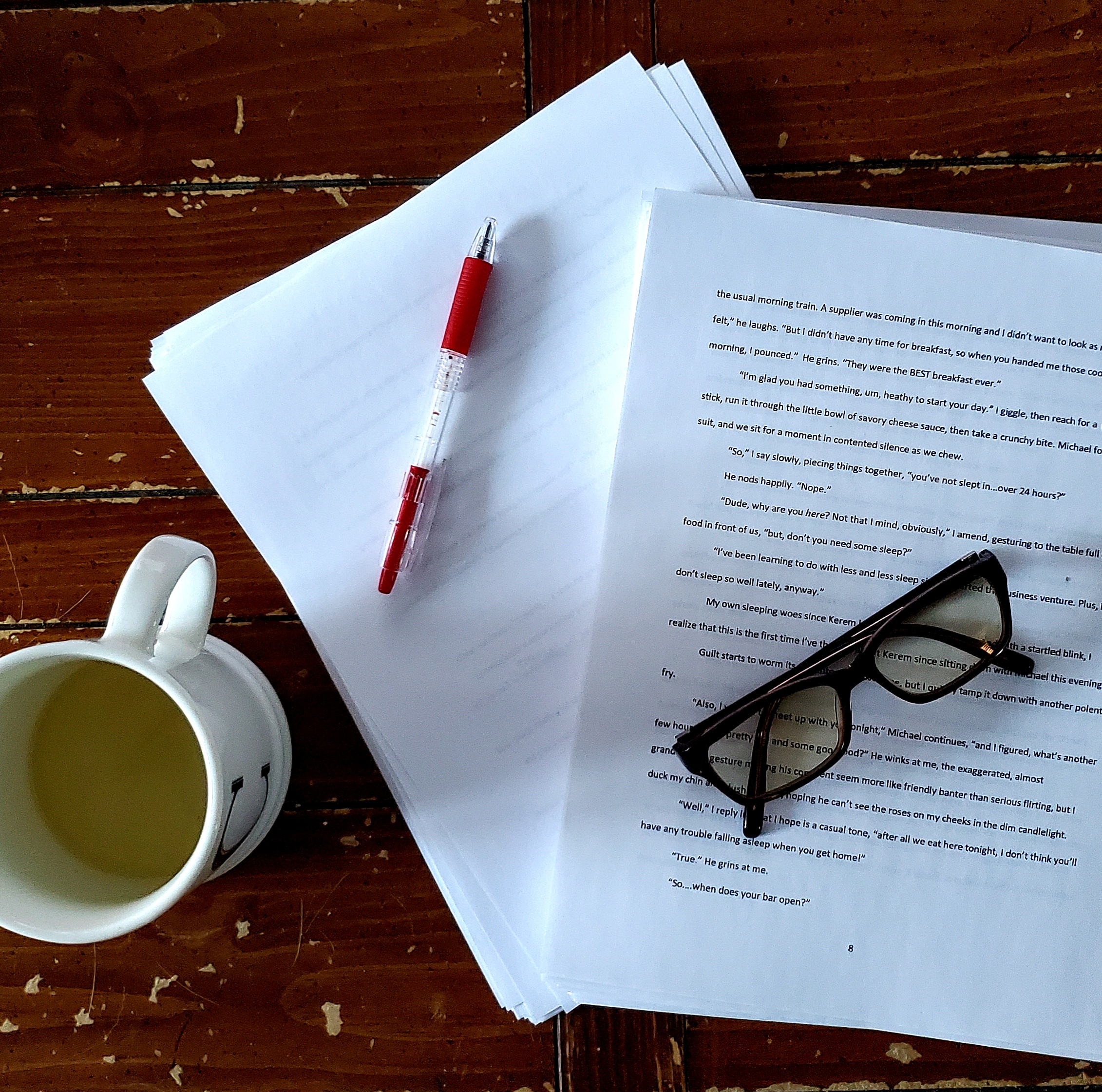 manuscript pages, pen, glasses, mug