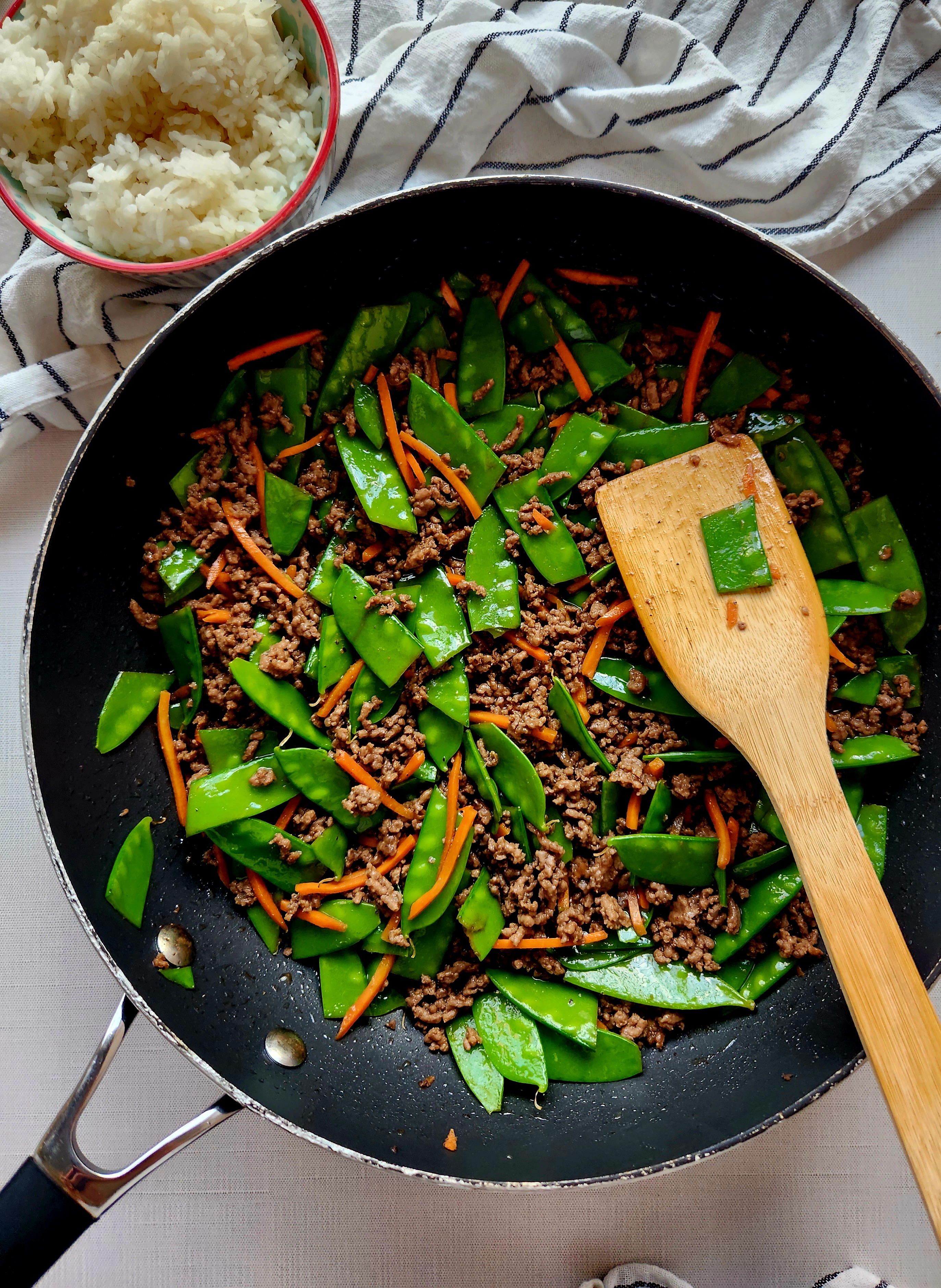 skillet of ground beef stir fry and wooden spatula