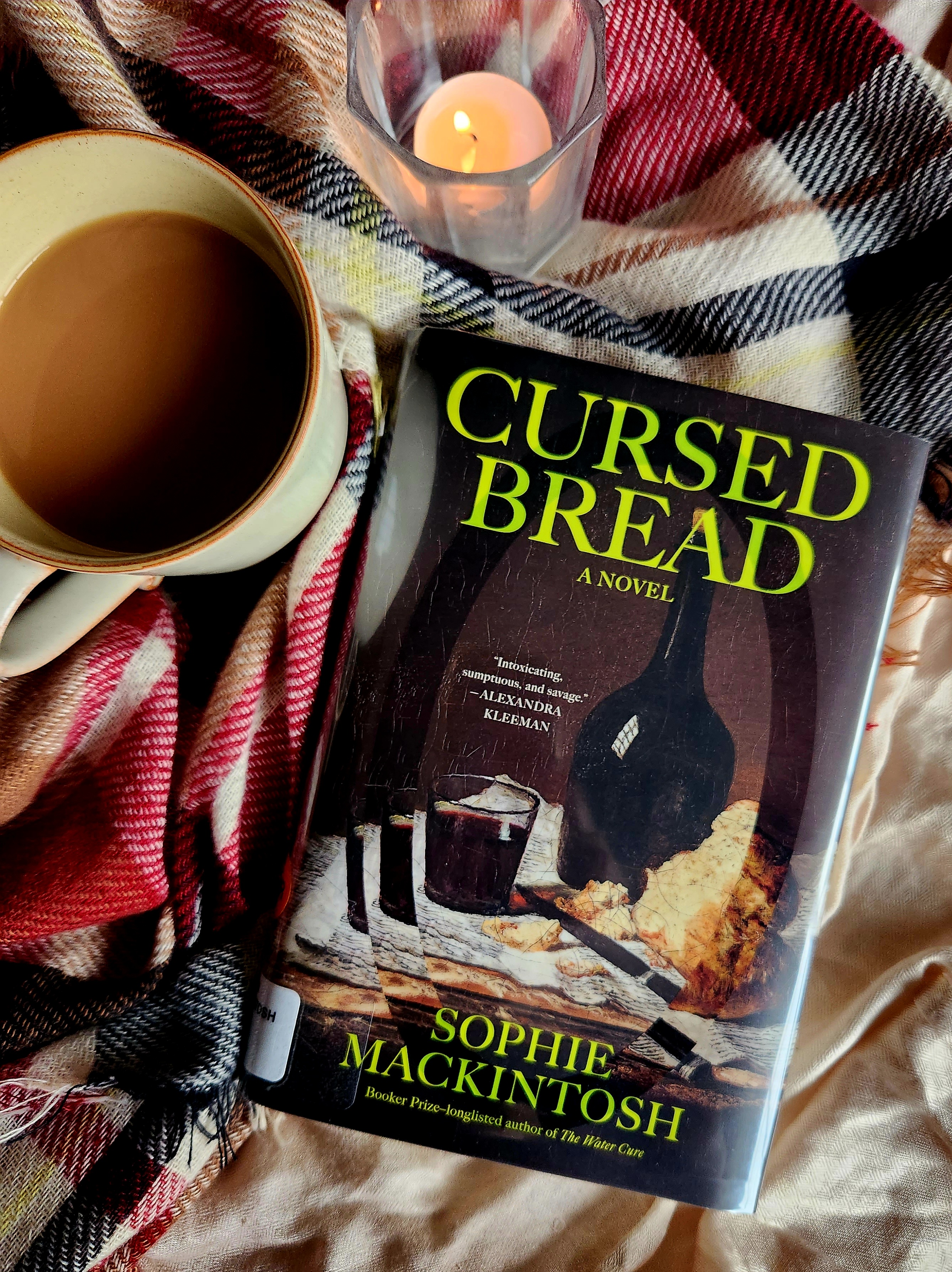 cursed bread book cover, scarf, mug of tea, candle