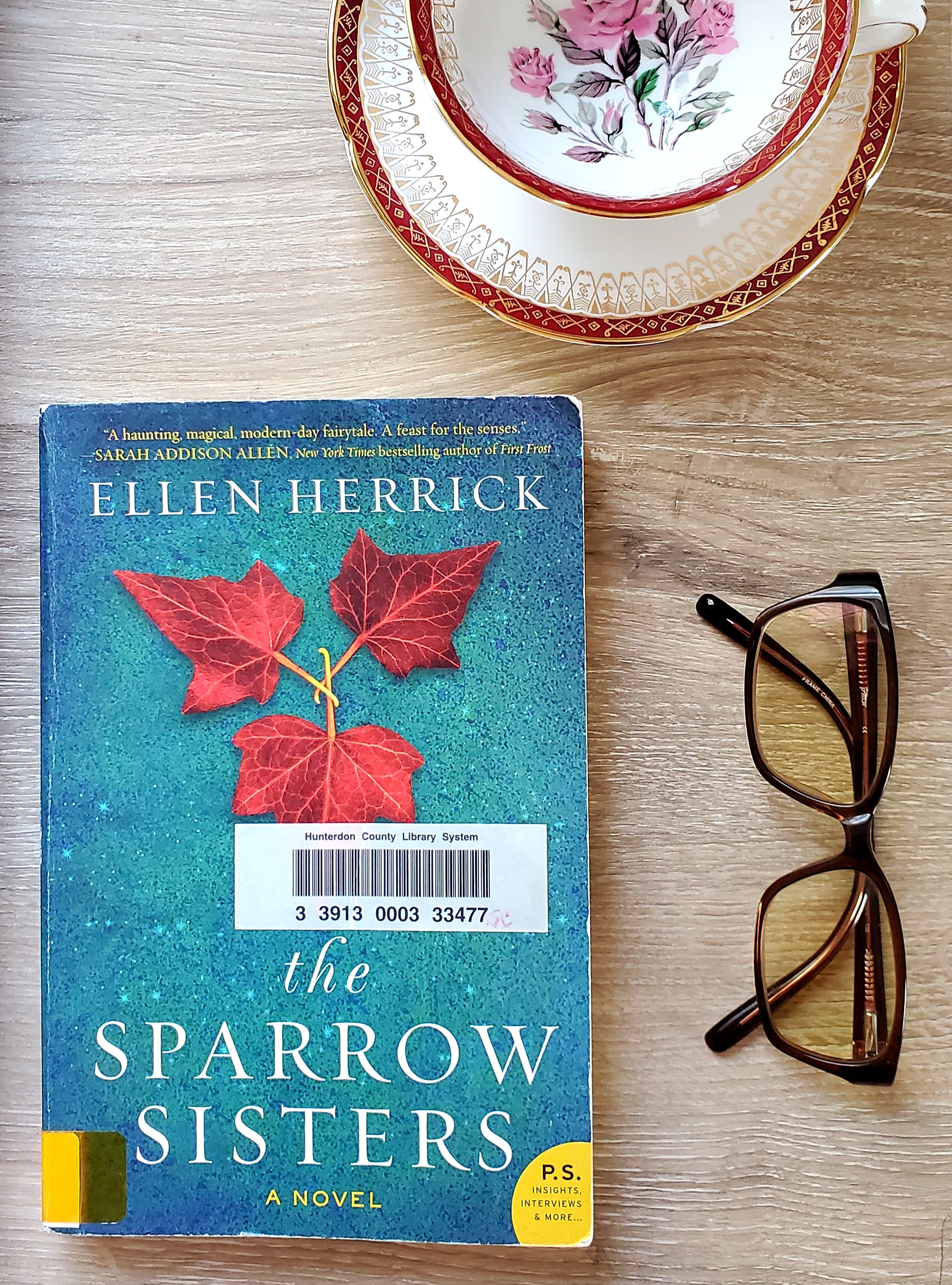 book cover of the sparrow sisters, a pair of reading glasses, and a teacup