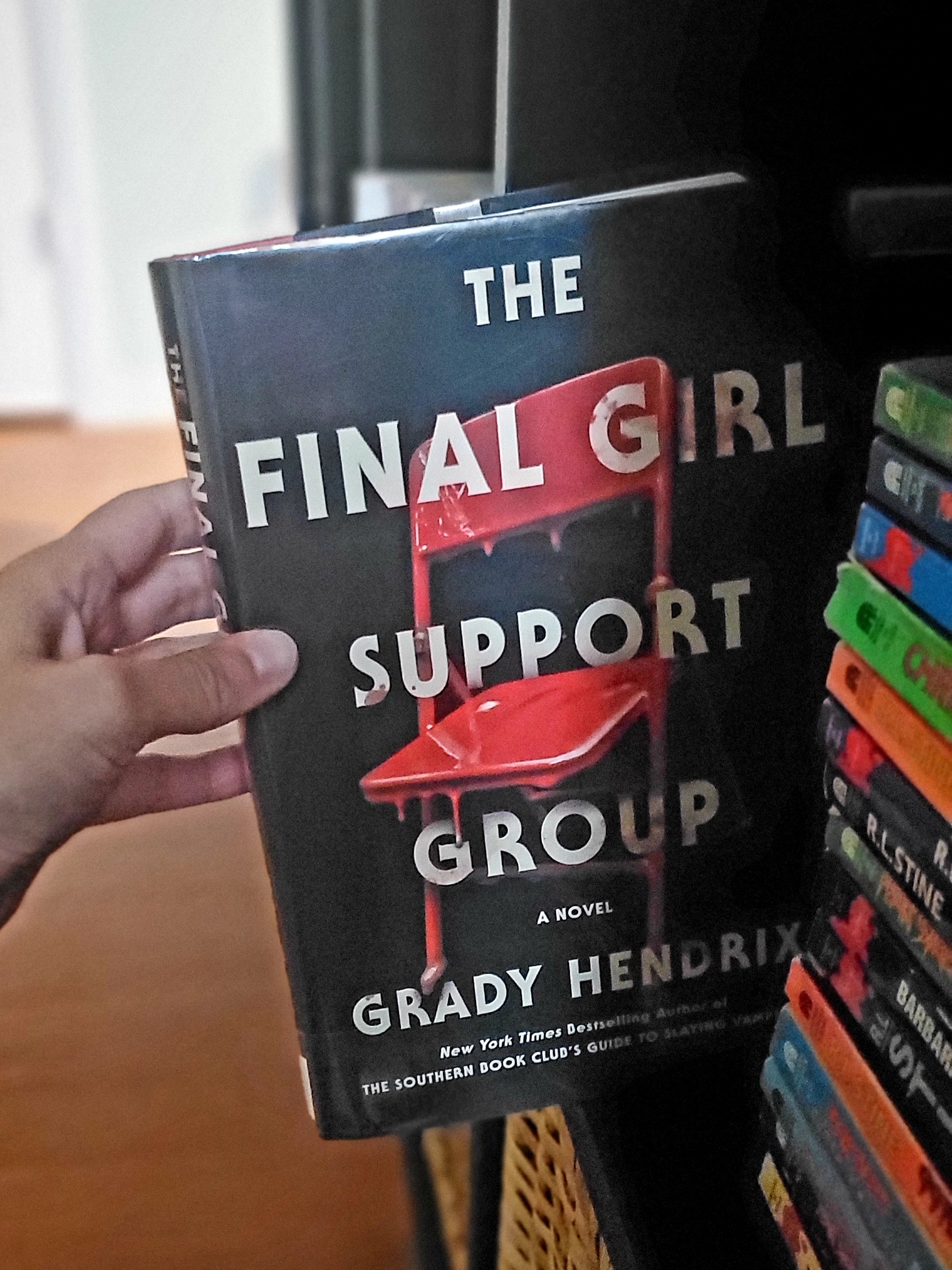The Final Girl Support Group by Grady Hendrix being pulled off a bookshelf.