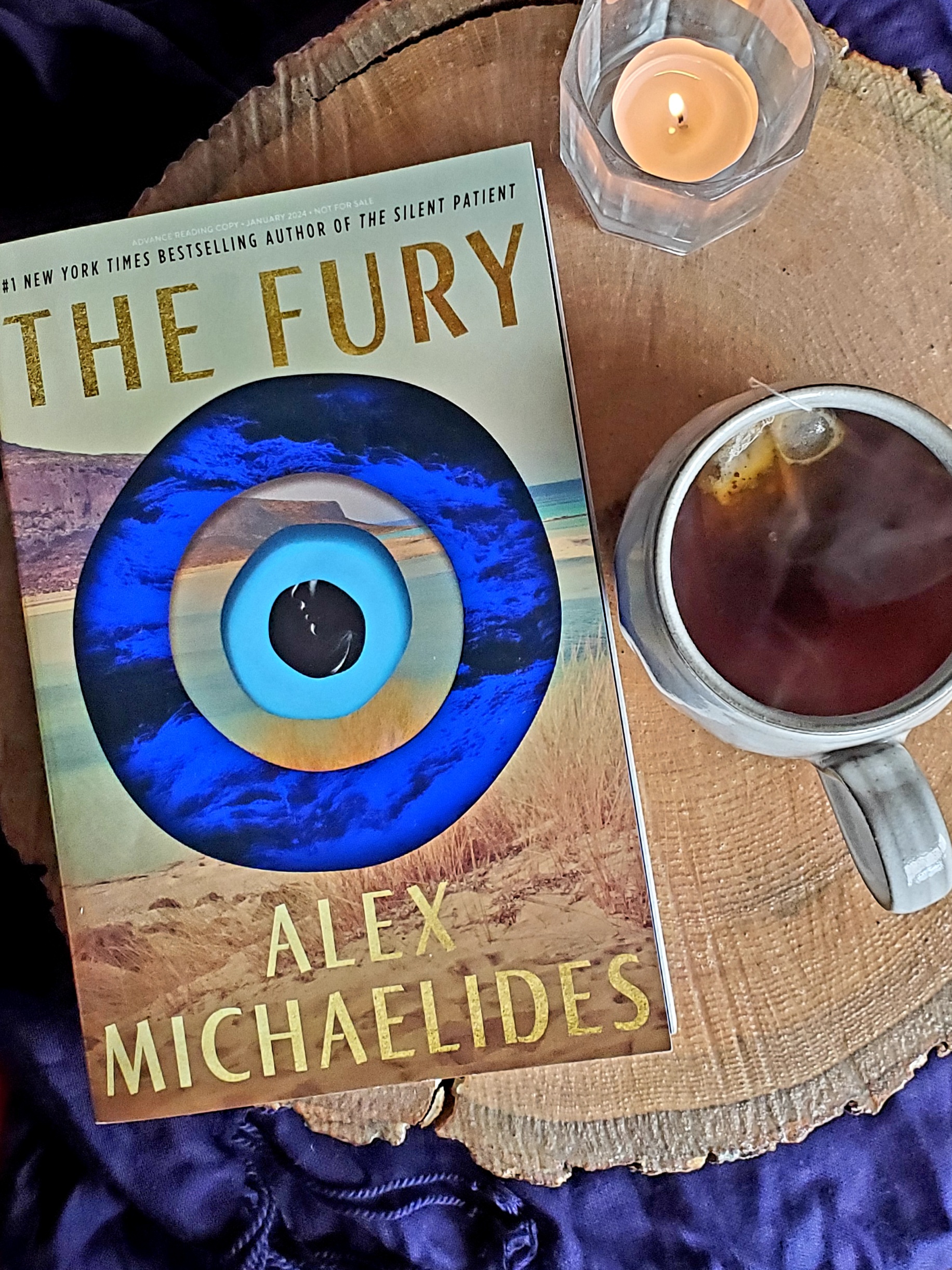 book cover for THE FURY by Alex Michaelides, mug of tea, candle
