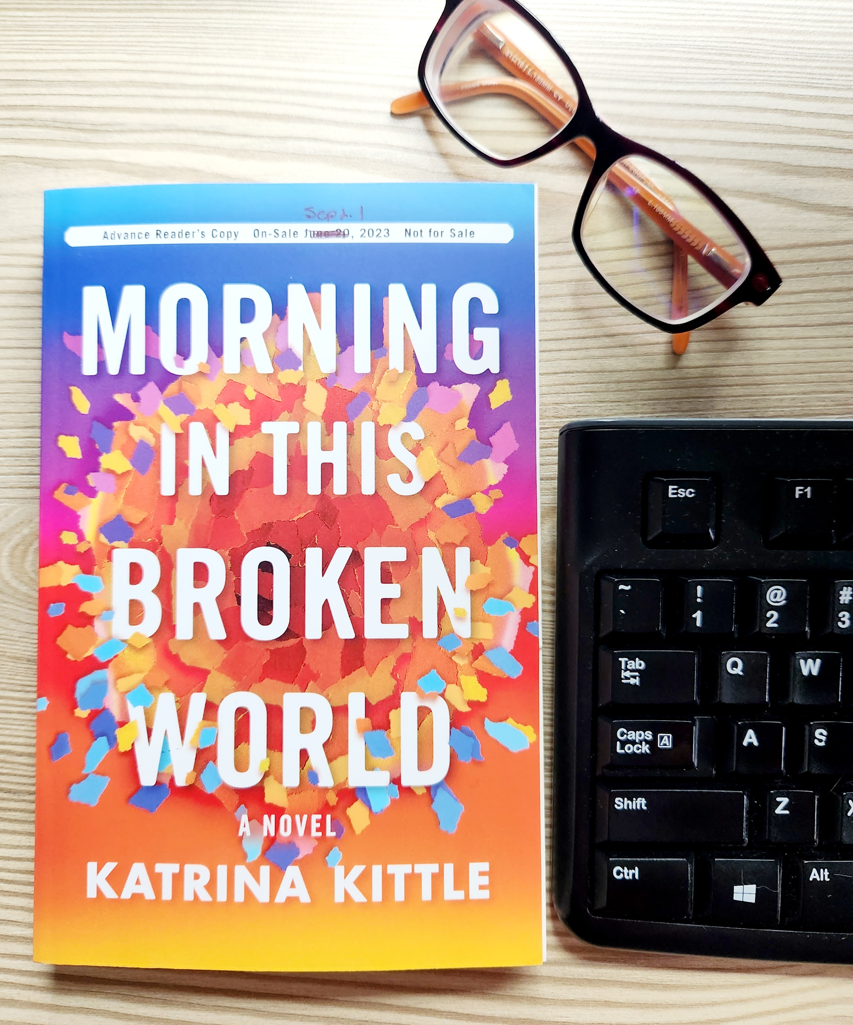 book cover of morning in this broken world; reading glasses; keyboard on a desk