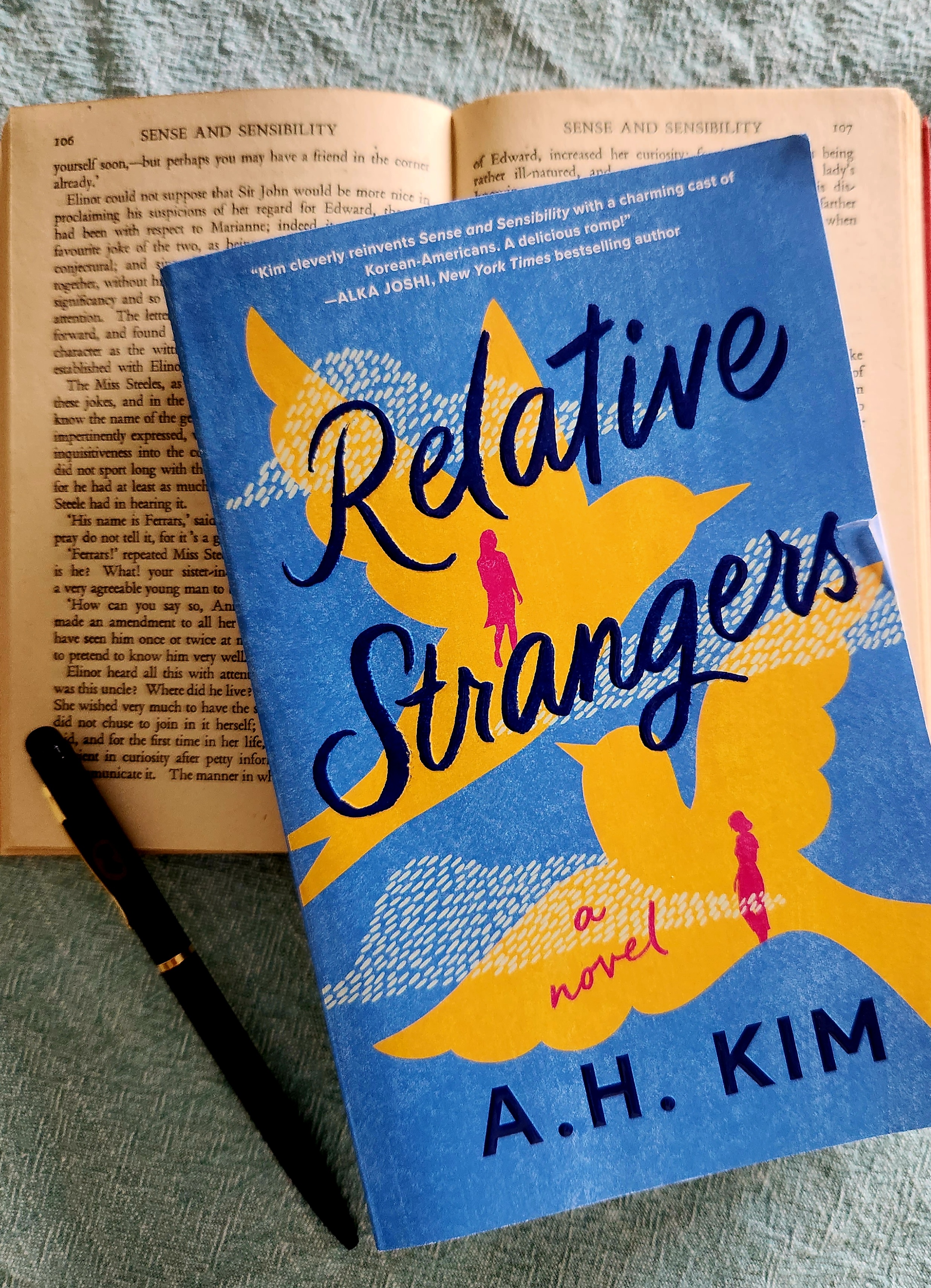 book cover of relative strangers by ah kim and sense and sensibility by jane austen in the background