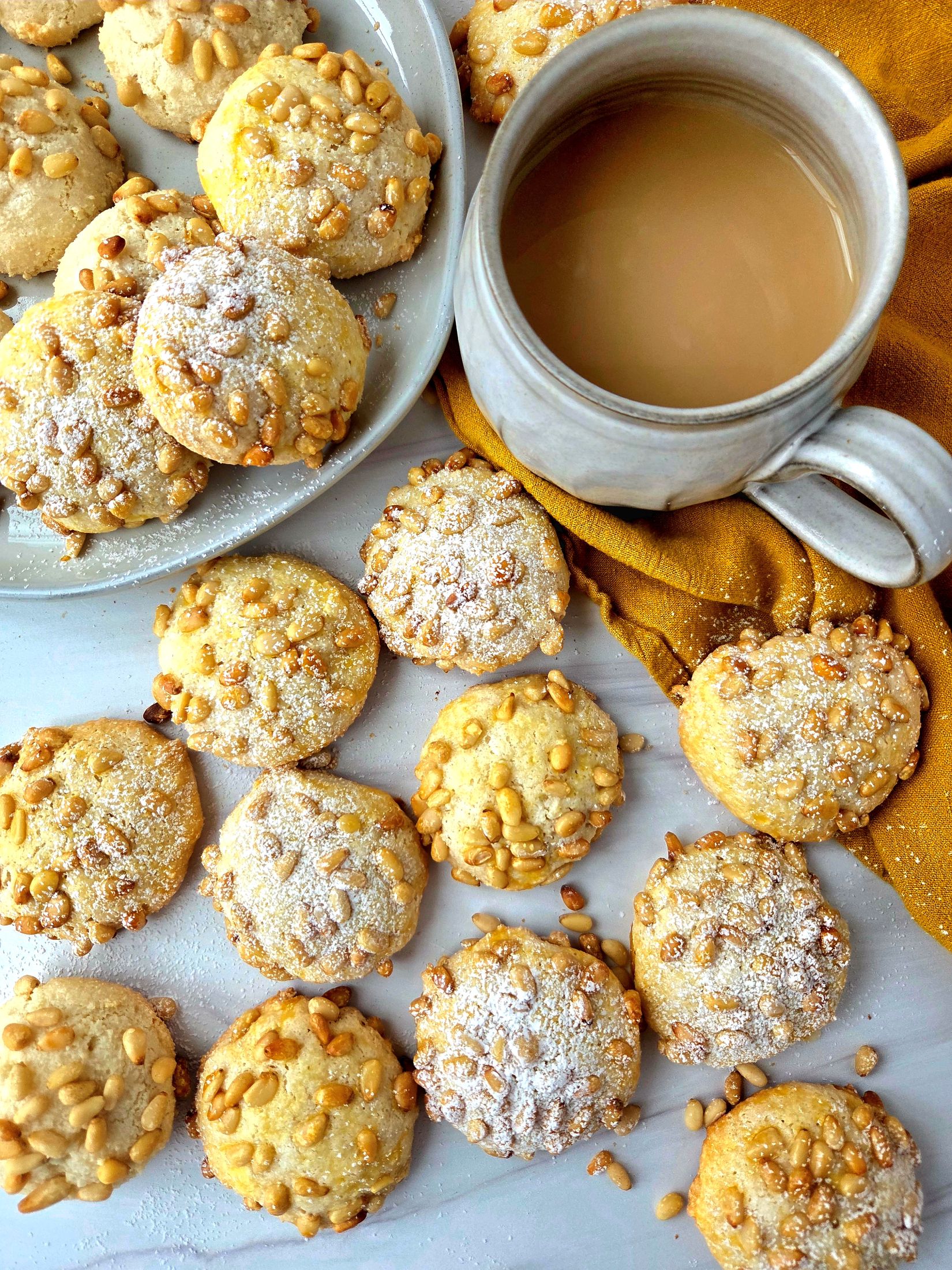 pignoli cookies on replica surfaces background with mug of tea